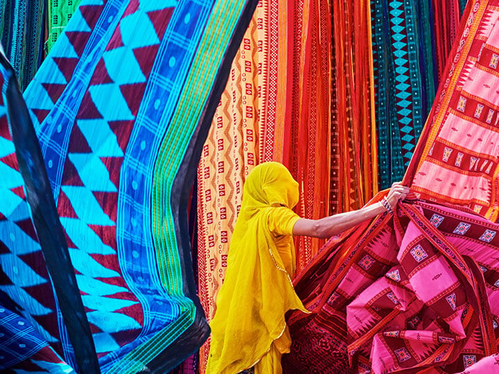 Woman in yellow sari collecting textiles in India